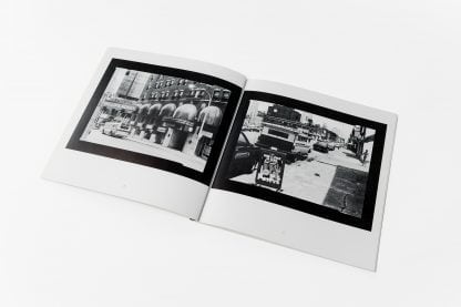 Otwarta książka, po obu stronach biało-czarne fotografie miasta.