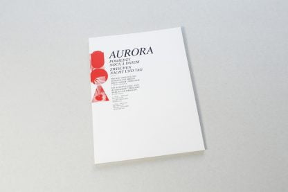 Biała okładka z czerwonym akcentem, czarnym napisem Aurora pomiędzy nocą a dniem.