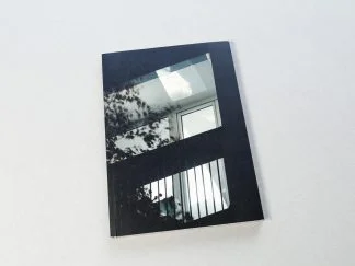 Okładka książki z czarno-białą fotografią oświetlonego balkonu w bloku.