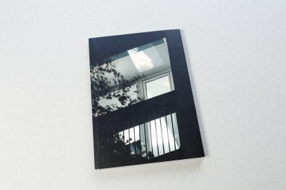 Okładka książki z czarno-białą fotografią oświetlonego balkonu w bloku.