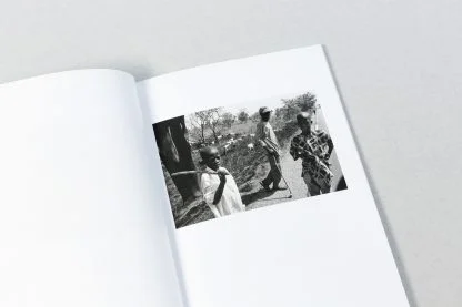 Czarno-białe zdjęcie w książce z trojgiem dzieci z kijami.